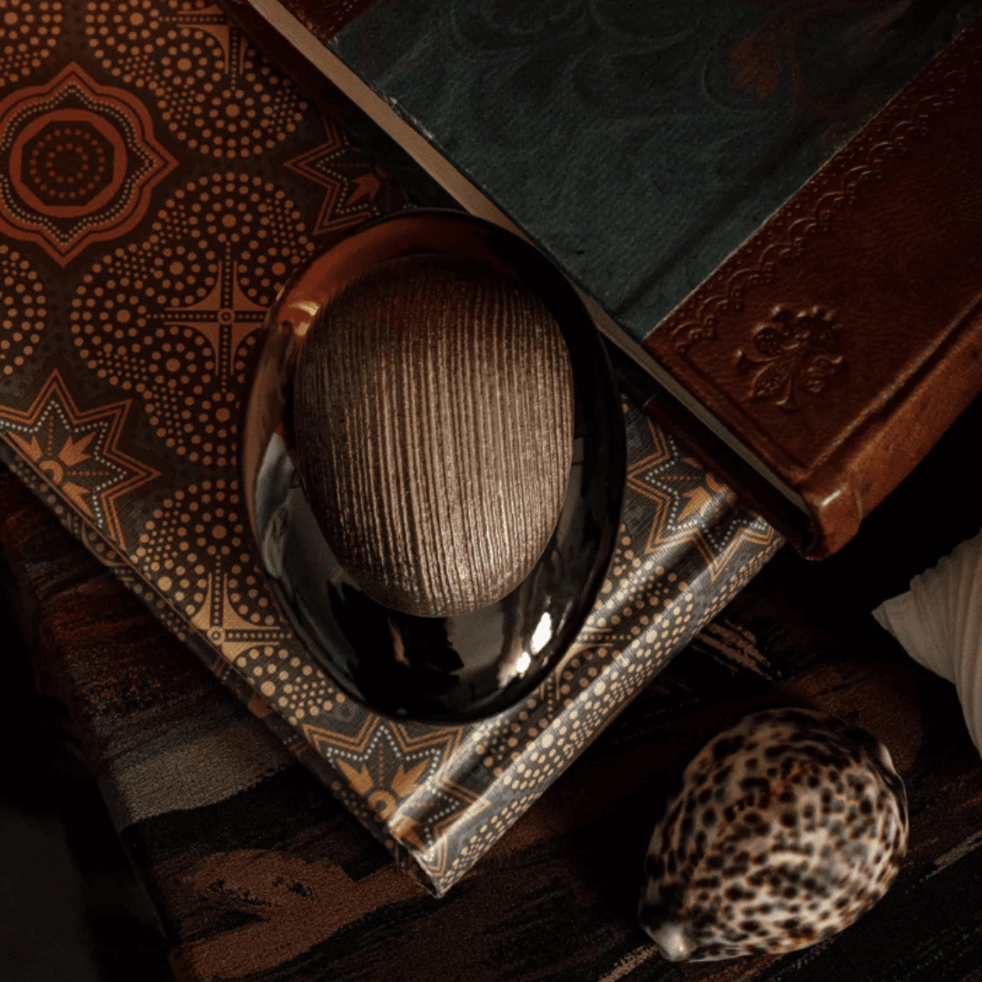 Majda Bekkali Mon Nom est Rouge Extrait de Parfum, Flakon auf kunstvollen Büchern und Stoff inszeniert, warm und orientalisch, erhältlich bei scent amor.