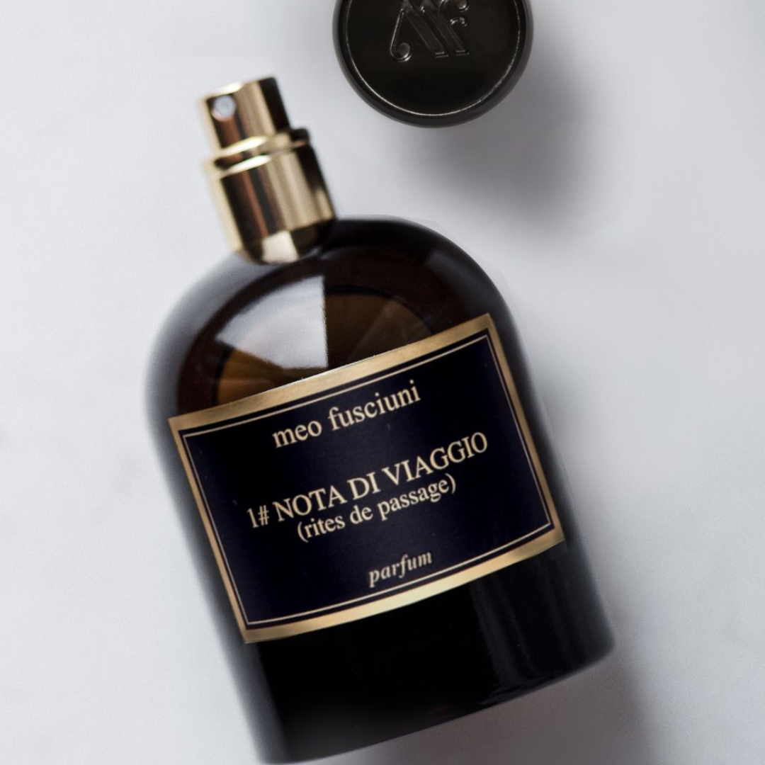Meo Fusciuni 1# Nota di Viaggio (Rites de Passages) Parfum, ein meditativ-rauchiger Nischenduft, dargestellt als liegender Glasflakon mit geöffnetem Sprühkopf und eleganter Goldakzentuierung, erhältlich bei scent amor.
