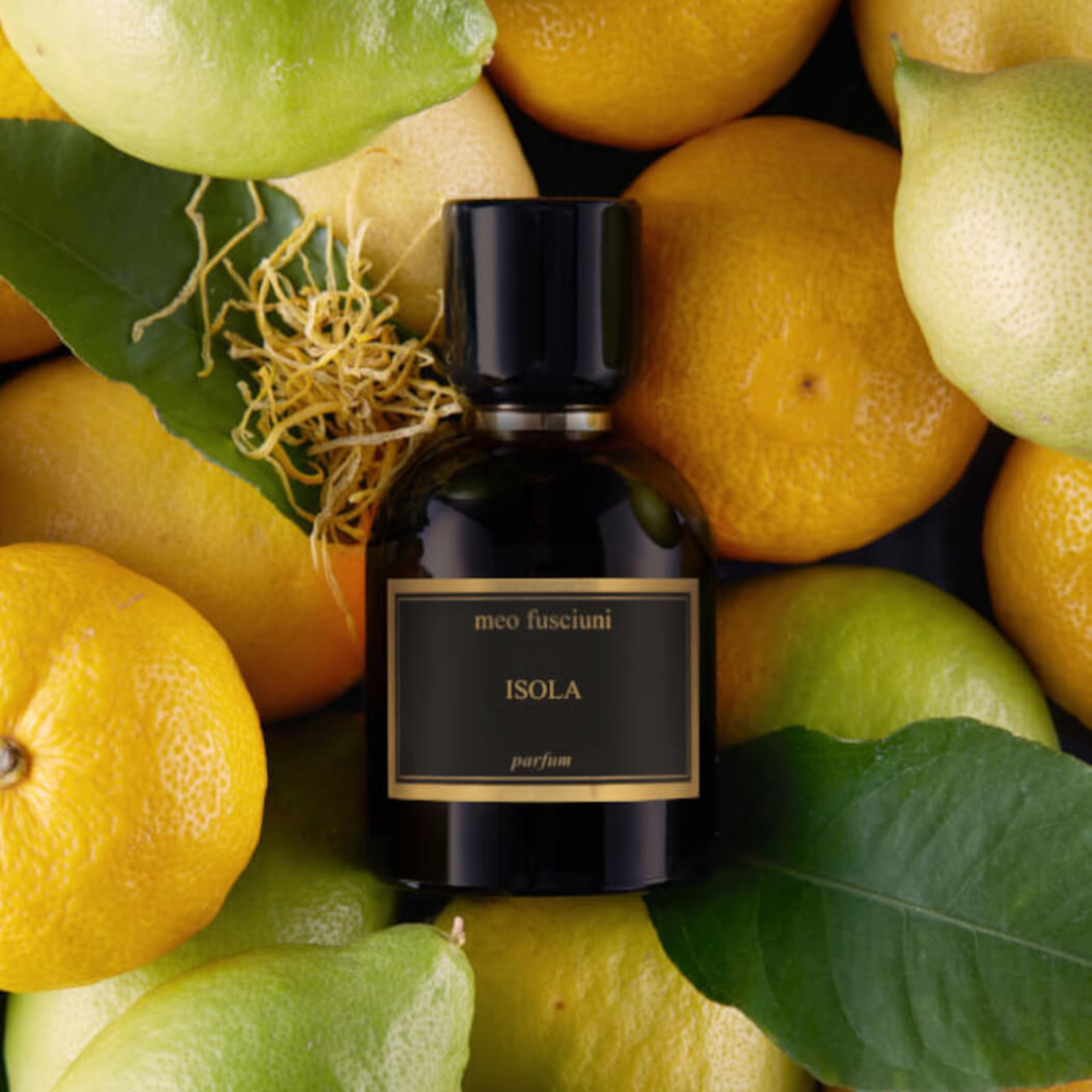 Duftbild mit dem Parfum Isola von Meo Fusciuni zwischen Zitronen und Blättern, lebendiger zitrischer Duft mit grüner Frische und sonniger Leichtigkeit, erhältlich bei scent amor.