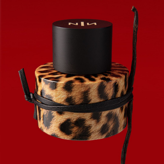 New Notes Felina Extrait de Parfum, Flakon mit Leopardenoptik vor intensiv rotem Hintergrund und schwarzer Schleife, ausdrucksstarker Nischenduft, erhältlich bei scent amor.