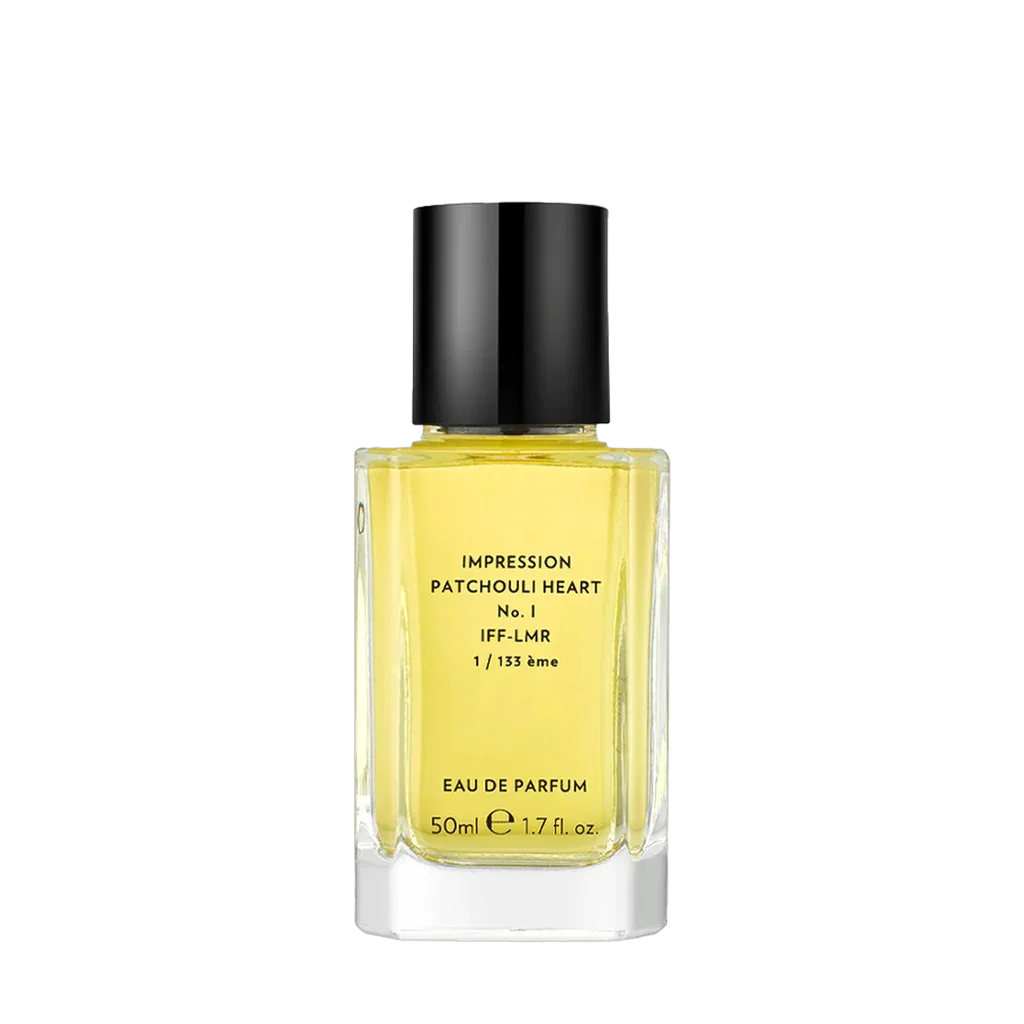 "Patchouli Heart I" von "Ostens": Ein quadratischer Flakon aus klarem Glas mit schwarzem Verschluss, gefüllt mit gelber Flüssigkeit. Etikett mit Text und Logo auf der Vorderseite.