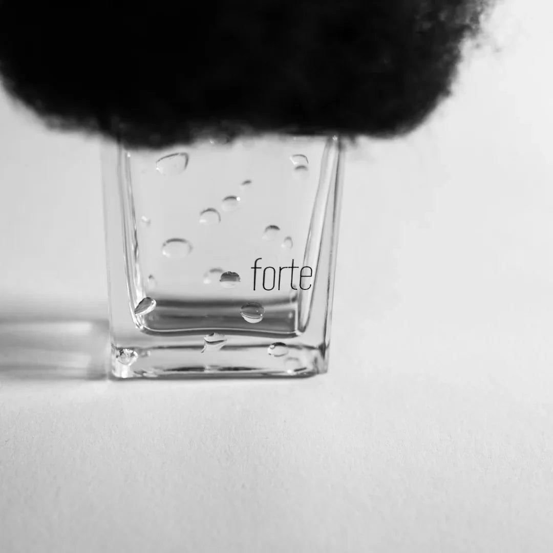 Quadratische Glasflasche mit Wassertropfen und schwarzem Flaschenverschluss, beschriftet mit "forte". Produkt: PIOGGIA FORTE, Hersteller: Filippo Sorcinelli.