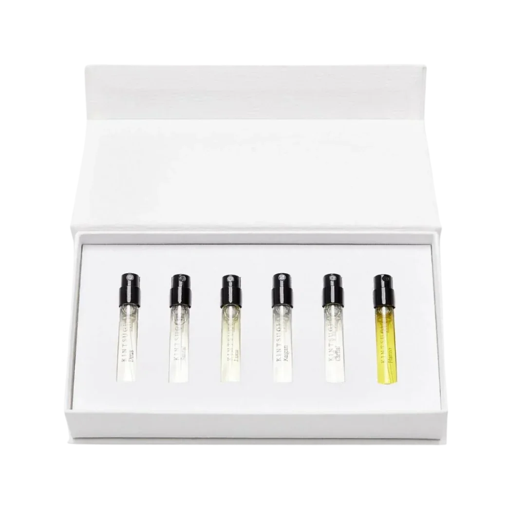 Sechs parfümierte Probefläschchen mit schwarzen Kappen, angeordnet in einer offenen weißen Geschenkbox. Produkt: Gift Set 8 x 2 ml von Kintsugi Perfumes.