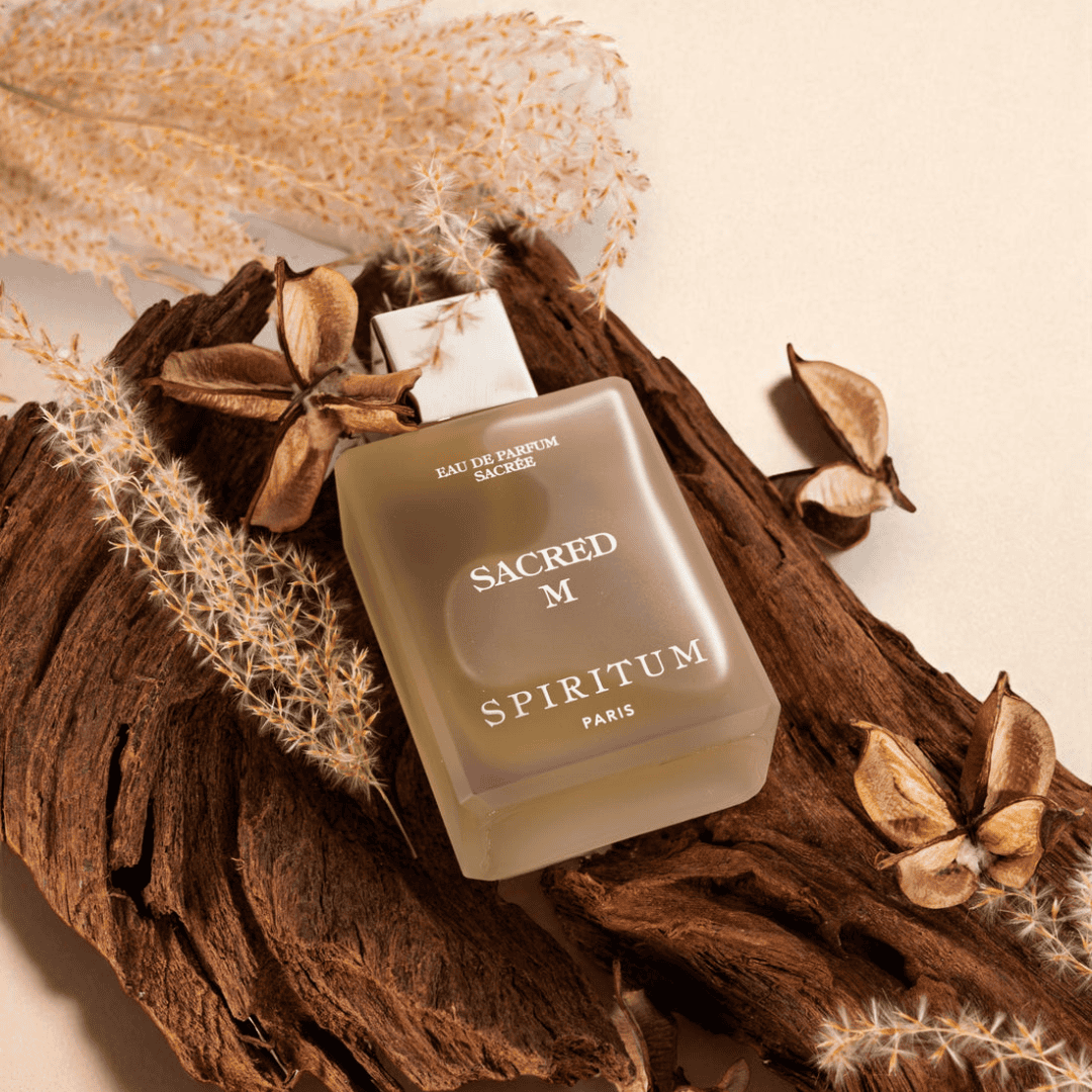 scent amor Spiritum Paris Sacred M Eau de Parfum, Flakon liegend auf Holz mit trockenen Pflanzen und Naturdetails, warmes aromatisches Ambiente, erhältlich bei scent amor