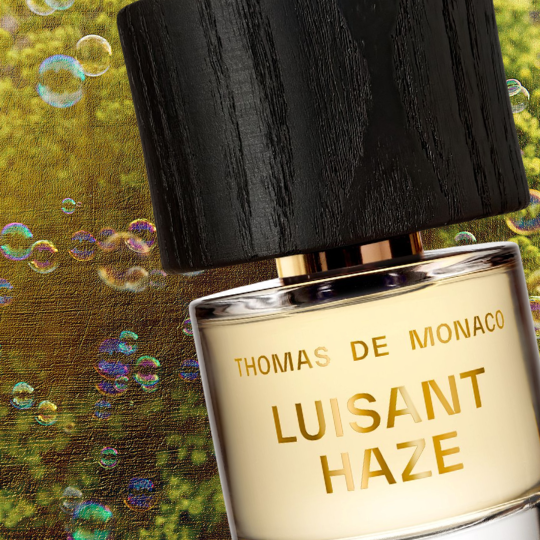 Thomas de Monaco Luisant Haze Extrait de Parfum, Detailaufnahme des Flakons mit schwebenden Seifenblasen und natürlichem Hintergrund, künstlerische Duftinszenierung, erhältlich bei scent amor.