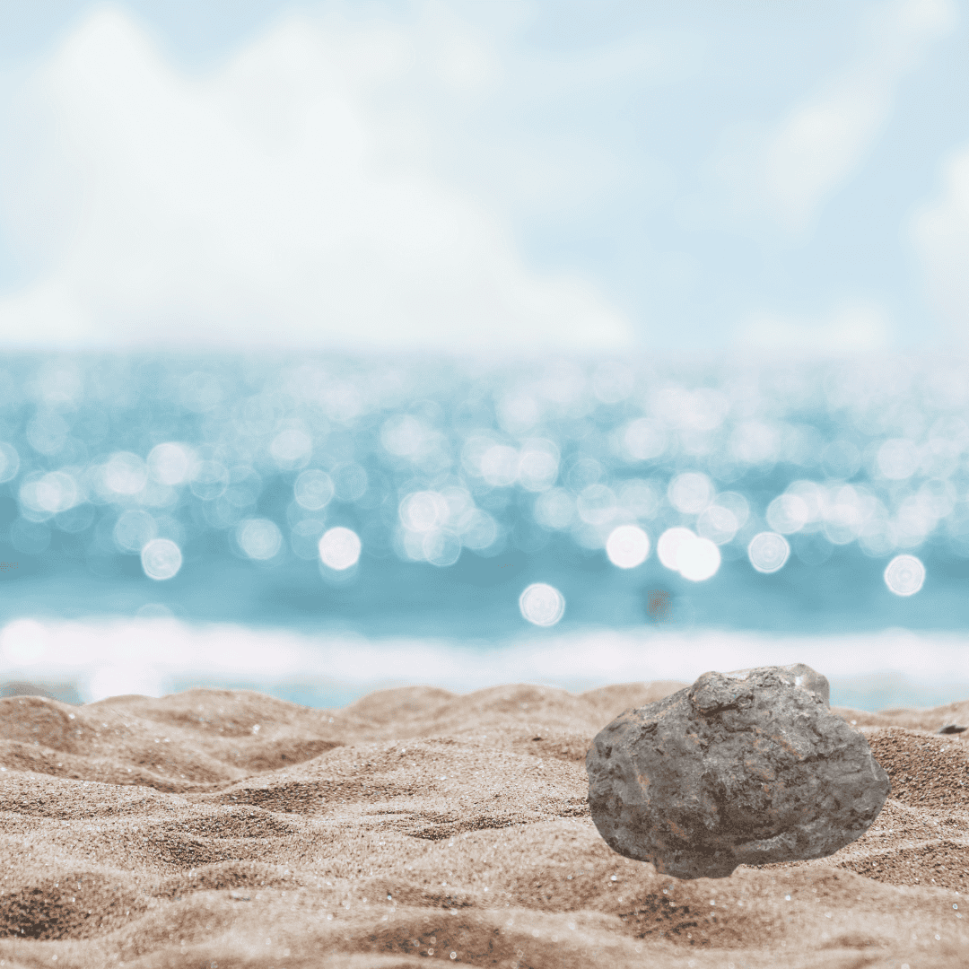 ein Stück Wal Ambra am Sandstrand mit glitzerndem Meer dahinter