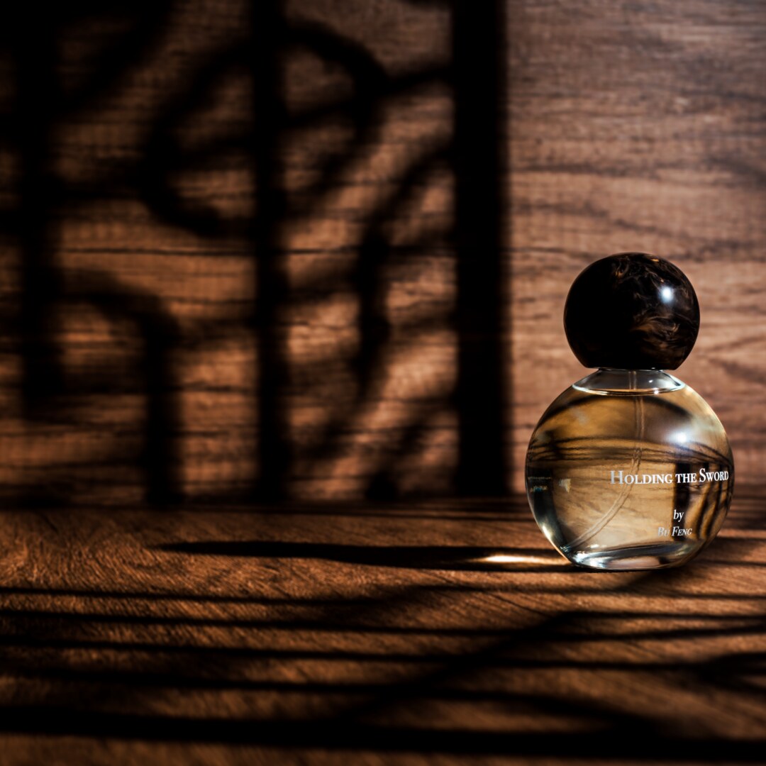 Bu Feng Eau de Parfum Holding the Sword Nischenduft Flakon vor Schattenwurf von einem Holzornament präsentiert bei scent amor Fachmann für feine Nischenparfums