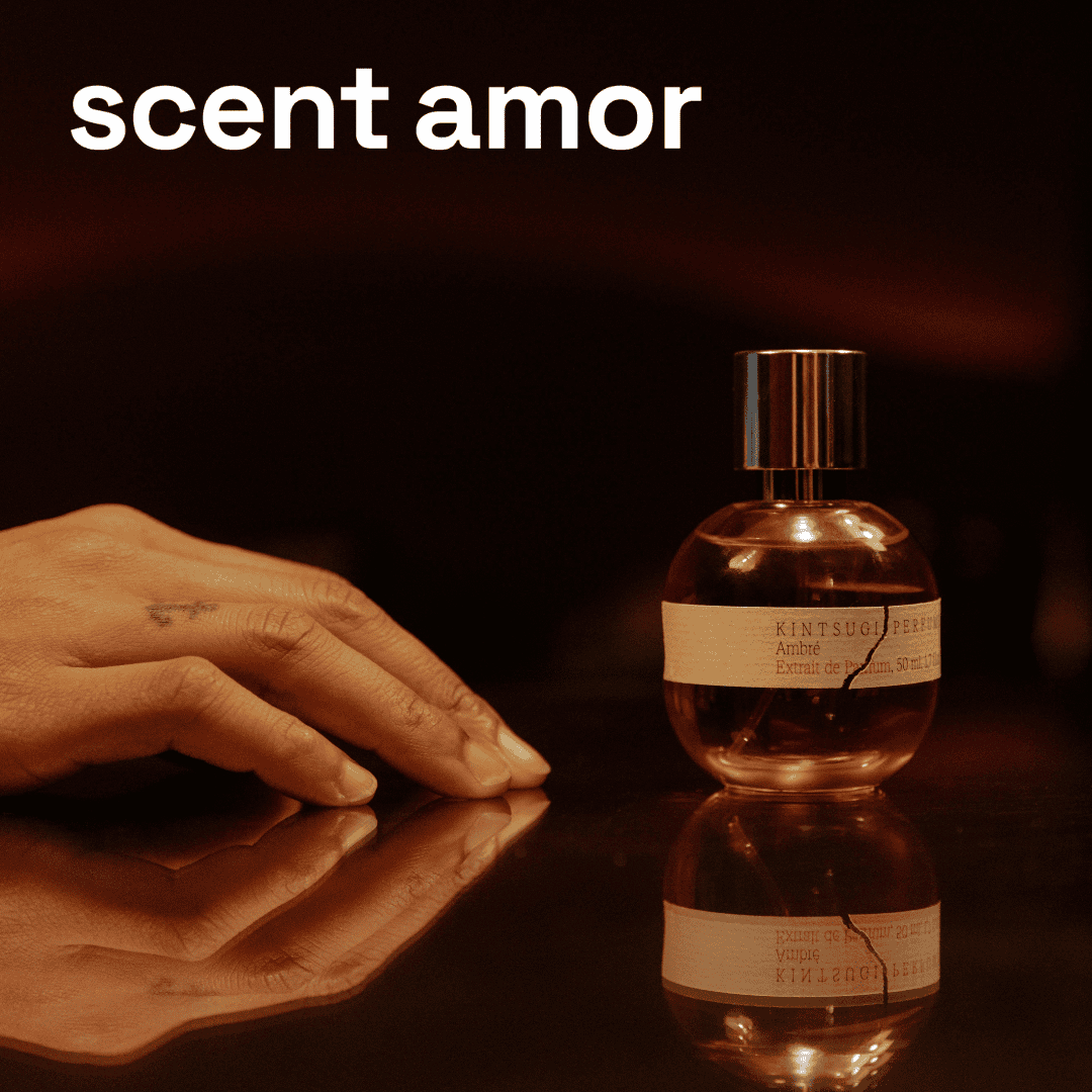 Kintsugi Perfumes Nischenduft Ambré auf Glastisch mit tätowierte Hand und scent amor Schriftzug