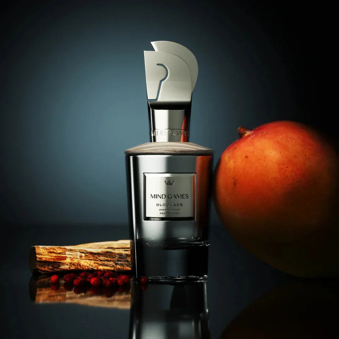 Flakon "Blockade" von Mind Games, silberner Verschluss, neben einer Mango und roten Beeren präsentiert bei scent amor deinem Fachmann für feine Nischenparfums