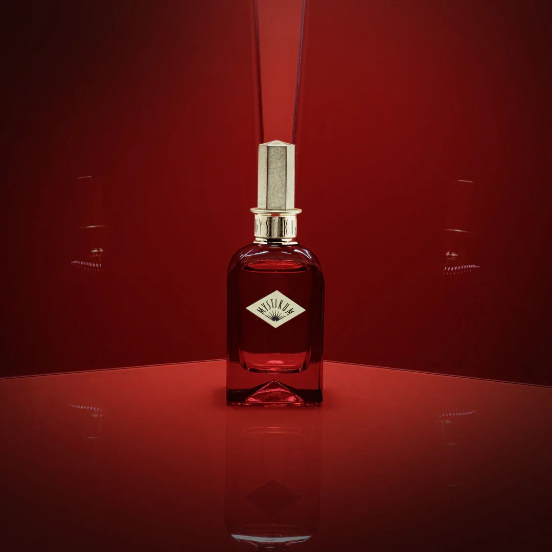 Mystikum The Empress' Kiss Eau de Parfum – der Flakon vor intensiv rotem Hintergrund, aus der Distanz inszeniert als Symbol königlicher Eleganz – entdecke diesen Duft bei scent amor