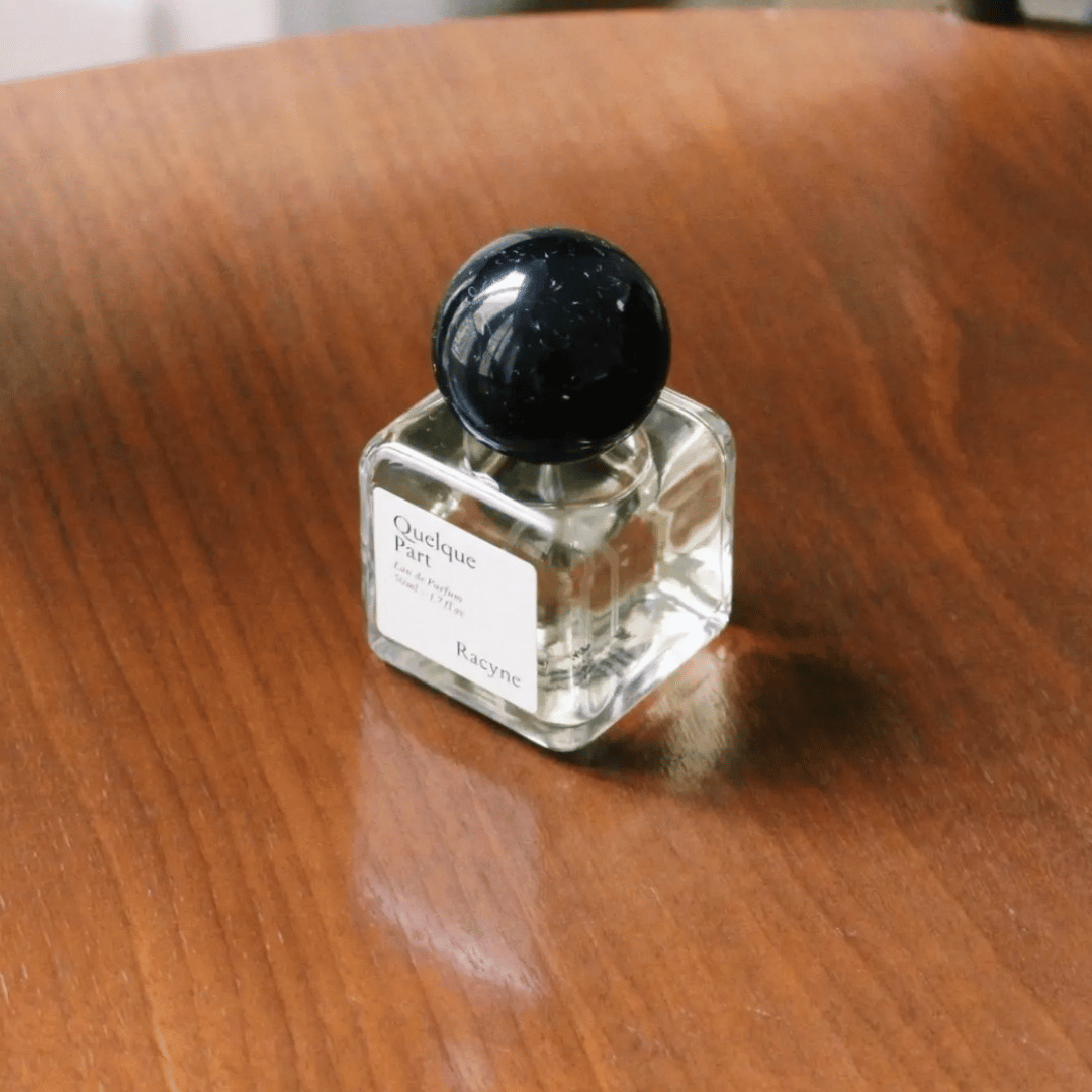 Racyne Quelques Part Eau de Parfum Nischenduft auf Tischplatte für scent amor der Spezialist für feinen Nischenparfums