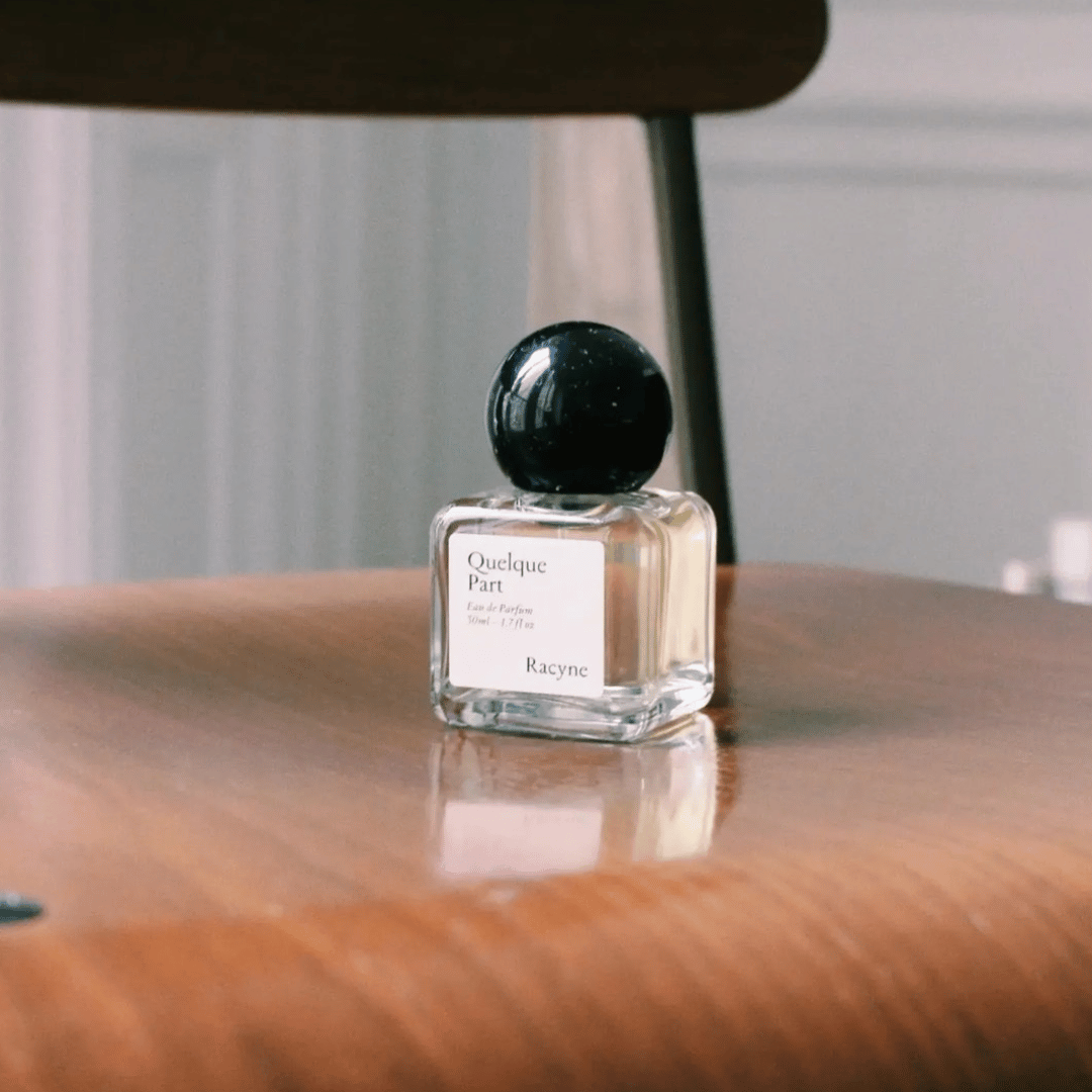 Racyne Quelques Part Eau de Parfum Nischenduft auf Holzsitz für scent amor Nischendüfte vom allerfeinsten