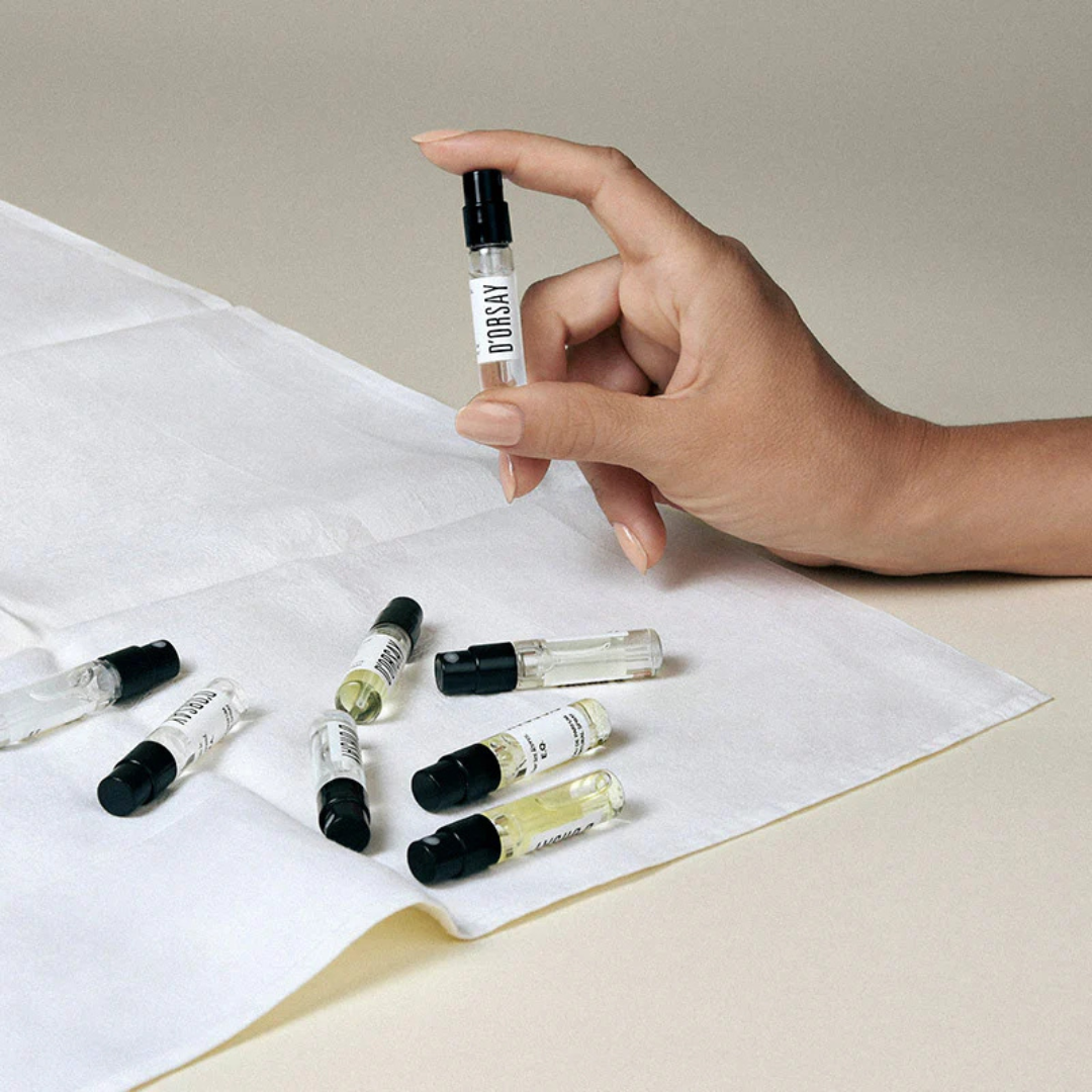 D’Orsay Les Découvertes Olfactives Discovery Set, Hand hält eine Duftprobe während weitere Proben auf einem weißen Tuch liegen, erhältlich bei scent amor.