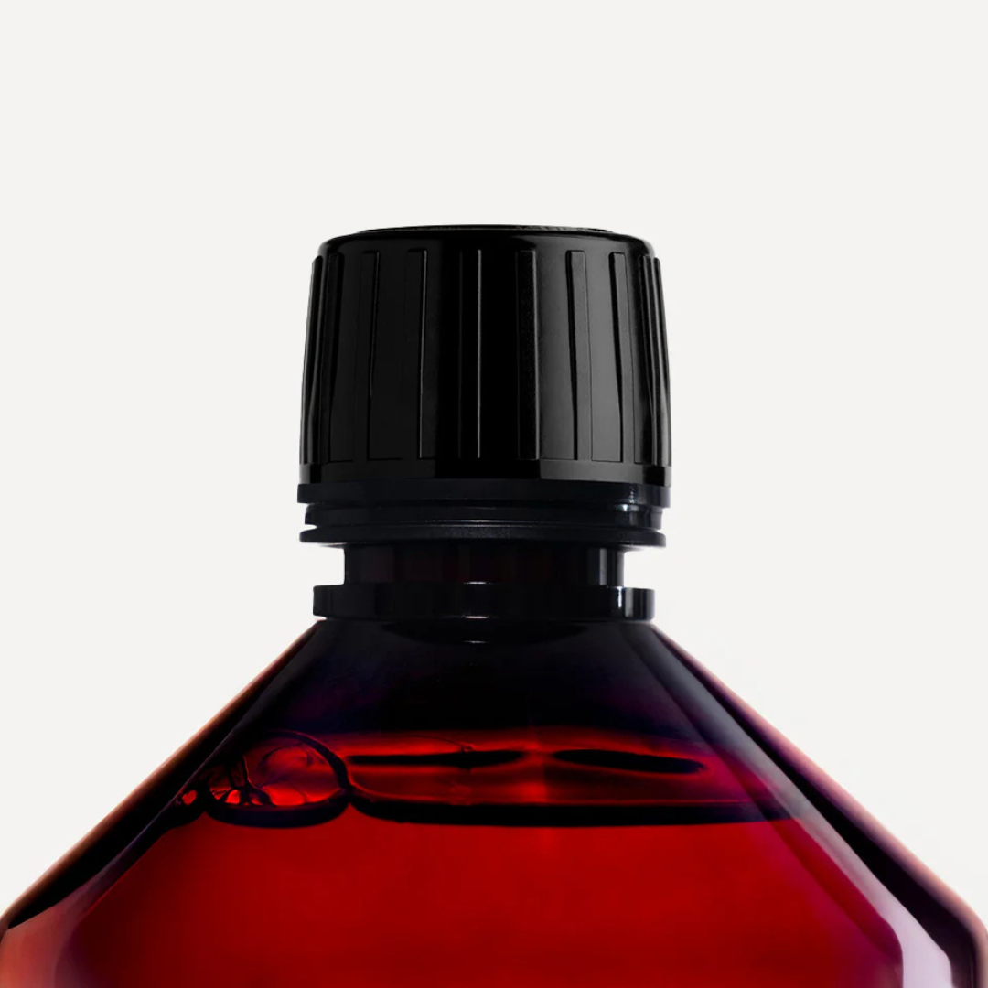 Essential Parfums Laundry Detergent, Detailaufnahme des Flaschenhalses und Deckels mit transparentem rötlichem Kunststoff und feinen Lichtreflexen, hochwertige Produktdarstellung, erhältlich bei scent amor.