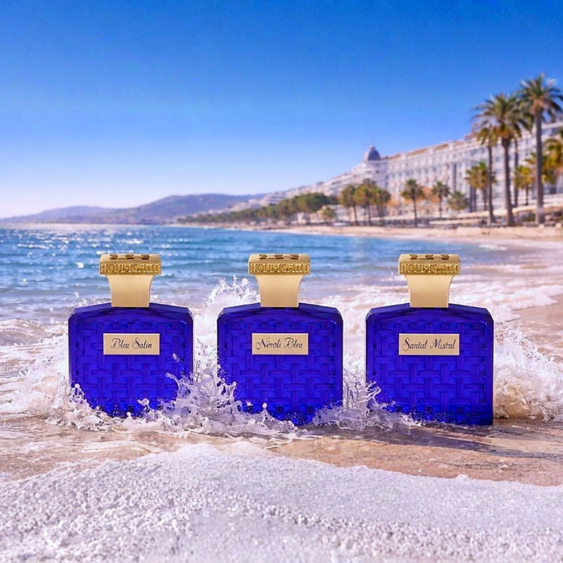 Houbigant Côte d'Azur Collection Eau de Parfum mit Bleu Salin, Néroli Bleu und Santal Mistral, tiefblaue Flakons am sonnigen Mittelmeerstrand mit Meereswellen inszeniert, erhältlich bei scent amor.