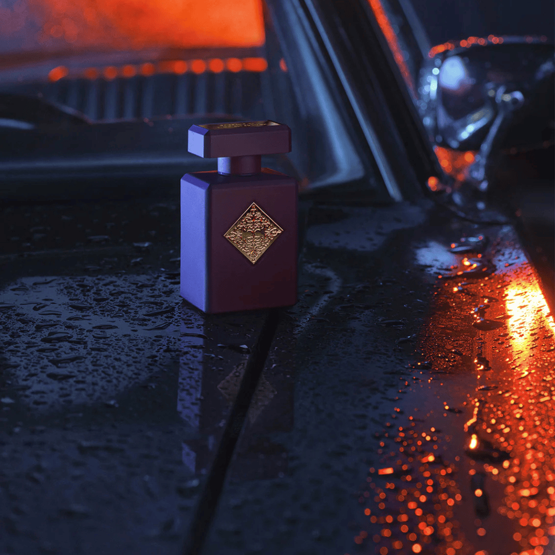 Initio Parfums Privés Can’t Get Enough Extrait de Parfum – Flakon auf nasser Autokarosserie im Lichtspiel, künstlerisch und geheimnisvoll bei scent amor