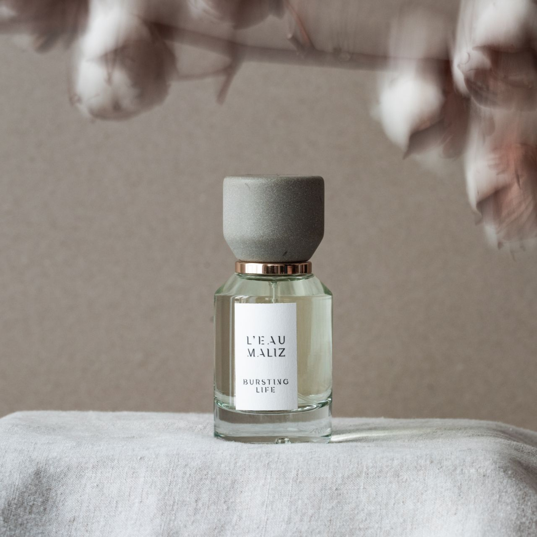 L’Eau Maliz Bursting Life Eau de Parfum, Flakon in Händen gehalten, persönlicher Moment und sanfte Alltagseleganz, erhältlich bei scent amor.