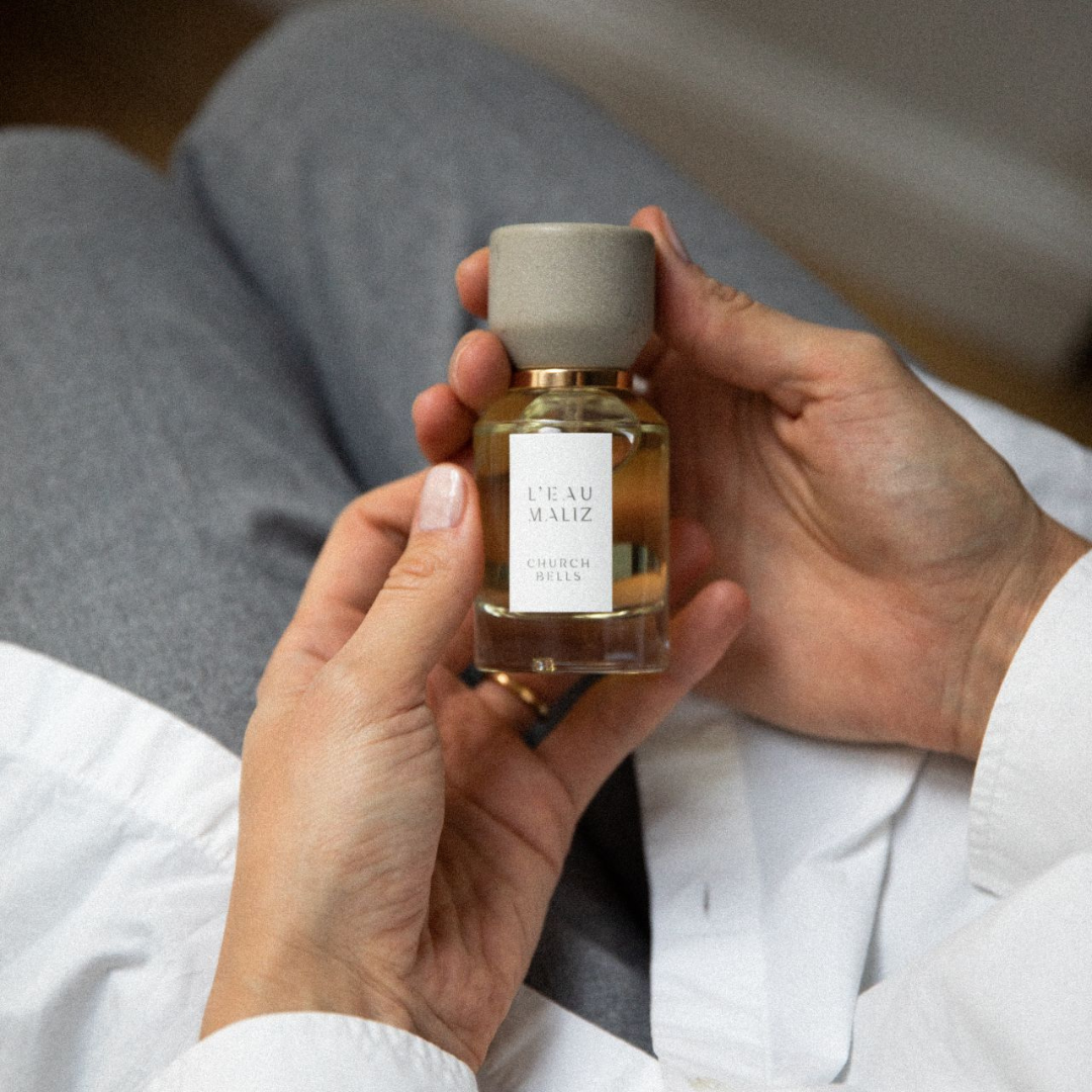 L’Eau Maliz Church Bells Eau de Parfum, Flakon in der Hand gehalten, warmes Lifestyle-Motiv mit persönlicher Note, erhältlich bei scent amor.