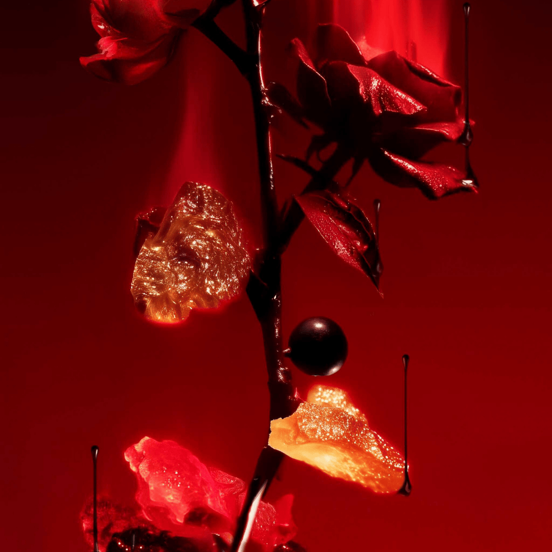 L’Entropiste Ensang Noir Eau de Parfum, künstlerische Detailaufnahme mit roten Blüten, Harz und dunklen Akzenten, sinnlich und geheimnisvoll, erhältlich bei scent amor.