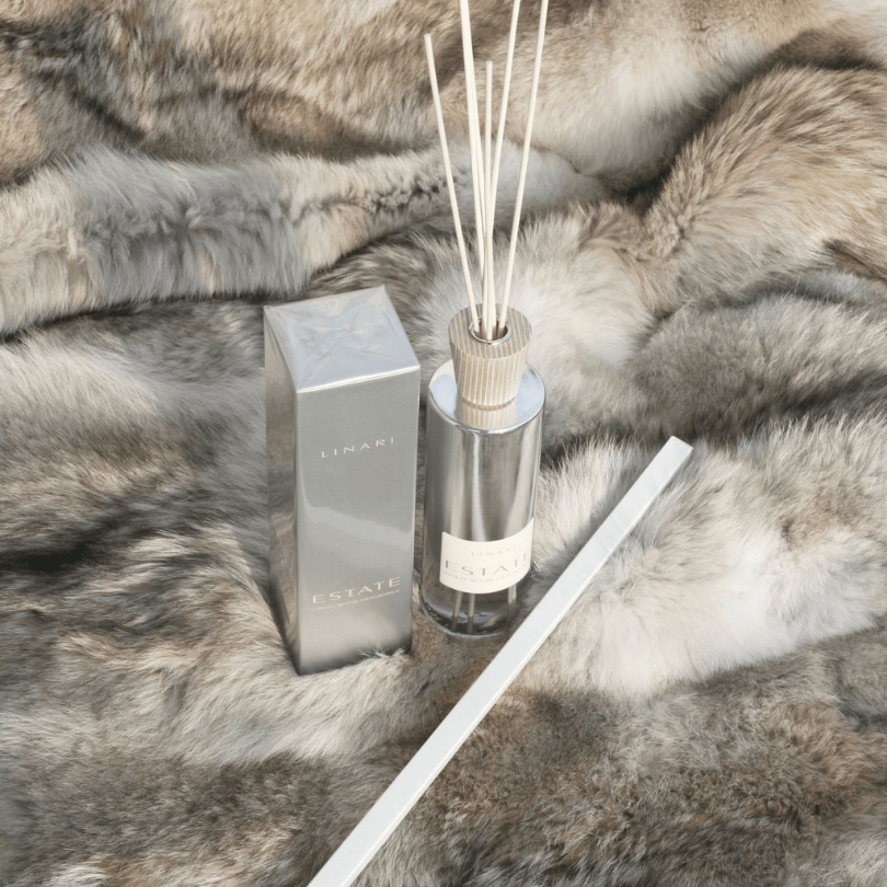 Linari Estate Diffuser, stilvoller Raumduft-Flakon mit Verpackung und Duftstäbchen auf weichem Fell, warm und luxuriös inszeniert, erhältlich bei scent amor.