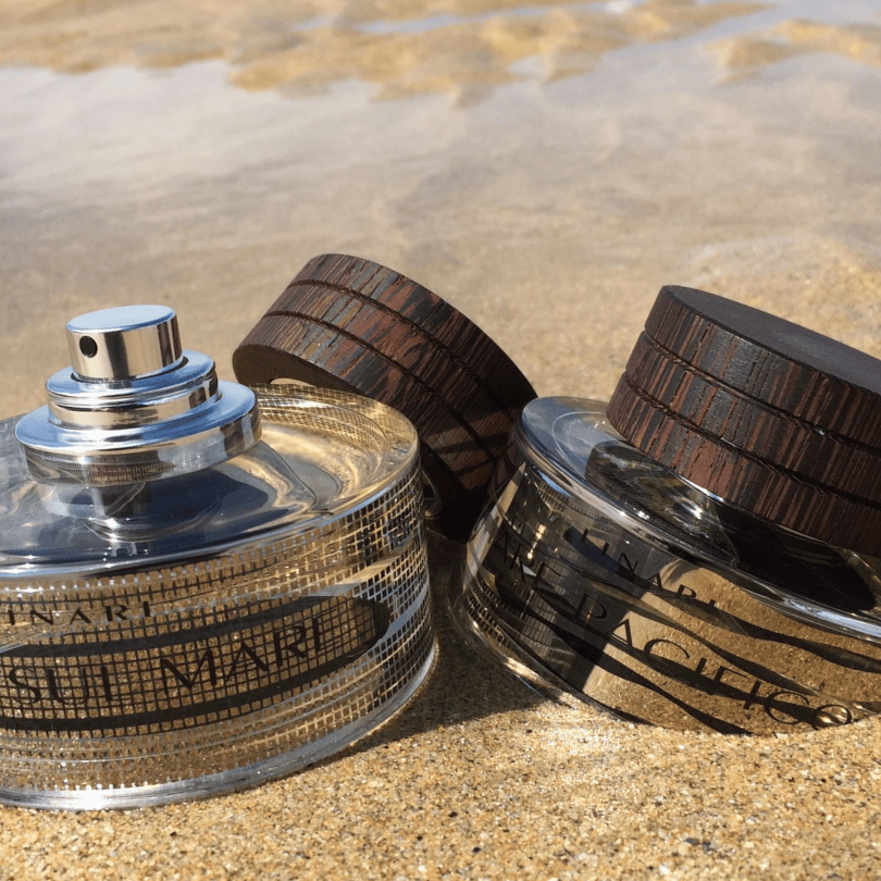 Linari Vista Sul Mare Eau de Parfum, elegante Duftflakons im Sand am Strand inszeniert, natürlich und sommerlich, erhältlich bei scent amor.