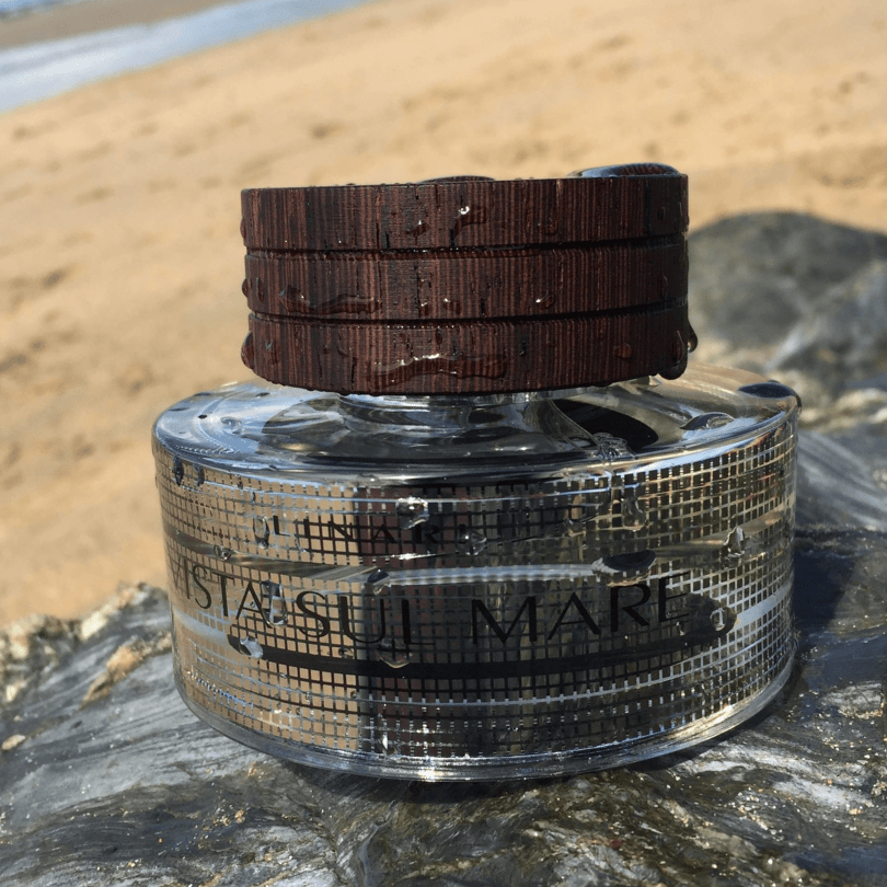 Linari Vista Sul Mare Eau de Parfum, luxuriöser Duftflakon am Strand mit Wasser und Sand, frisch und maritim inszeniert, erhältlich bei scent amor.