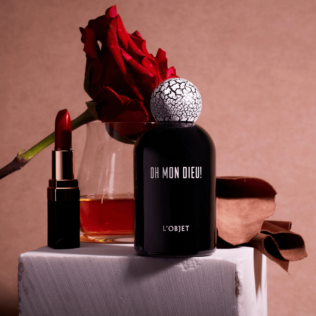 L’Objet Oh Mon Dieu! Eau de Parfum, sinnliche Duftkomposition mit Noten von Rose, Leder und Likör, inszeniert mit rotem Lippenstift und Blüte, erhältlich bei scent amor.