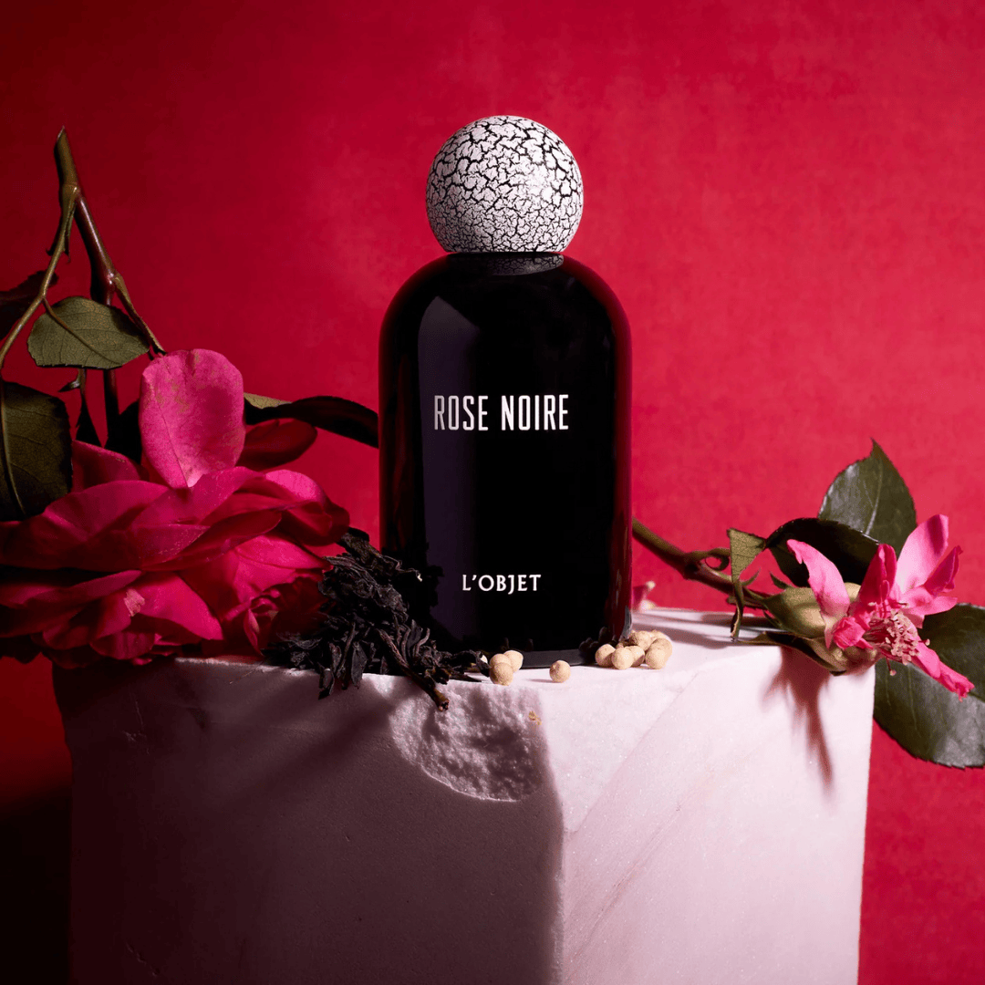L’Objet Rose Noire Eau de Parfum, luxuriöse Duftkomposition mit schwarzen Rosen, Tee und Gewürzen, inszeniert auf rotem Hintergrund mit floralen Akzenten, erhältlich bei scent amor.