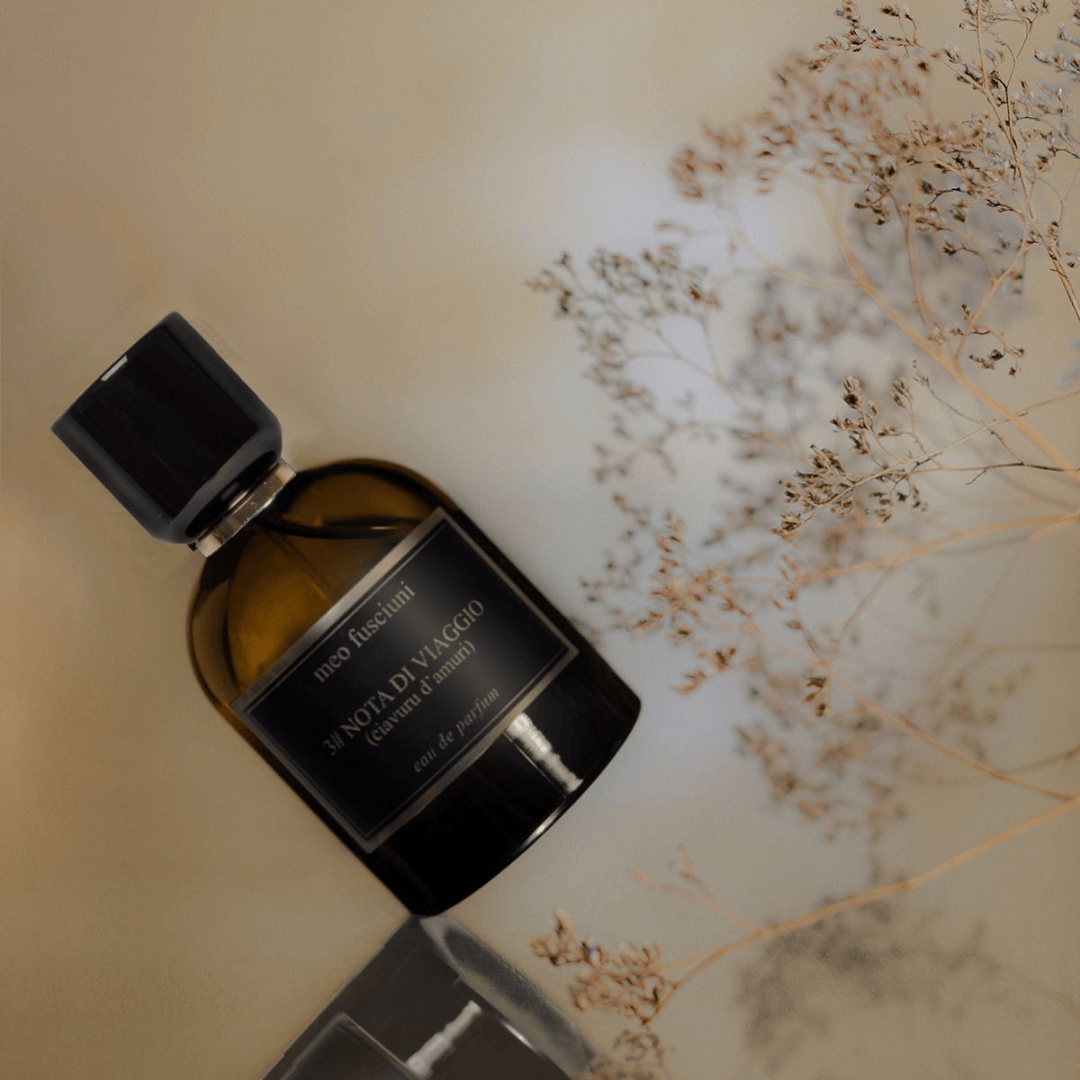 Meo Fusciuni 3# Nota di Viaggio (Ciavuru d’Amuri) Eau de Parfum, liegend arrangierter Flakon neben feinen Trockenblumen auf hellem Untergrund, poetische und ruhige Bildstimmung, erhältlich bei scent amor.