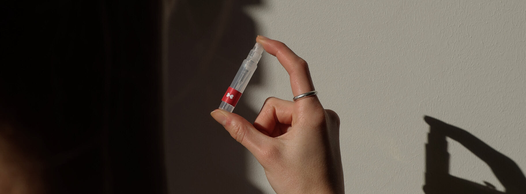 Eine Parfumprobe abgefüllt in einem Tester mit scent amor Logo. Der tester wird in einer Hand gehalten.