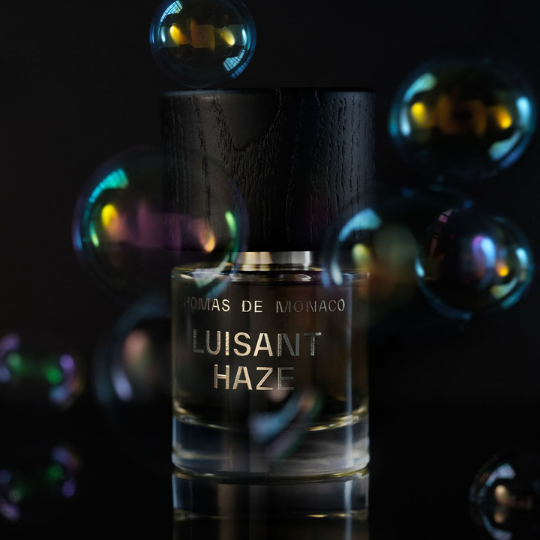 Thomas de Monaco Luisant Haze Extrait de Parfum, Flakon in dunkler Atmosphäre mit schillernden Blasen und reflektierendem Glas, geheimnisvoller Duft, erhältlich bei scent amor.